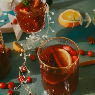 glass of citrus mulled wine with orange slices and cinnamon sticks