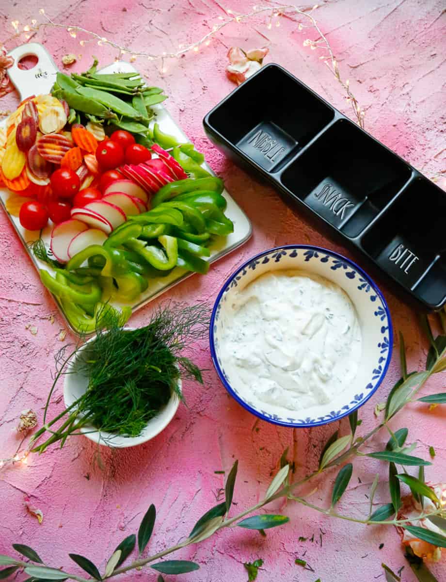 Ranch dressing with a black dip jar with veggies and fresh herbs 