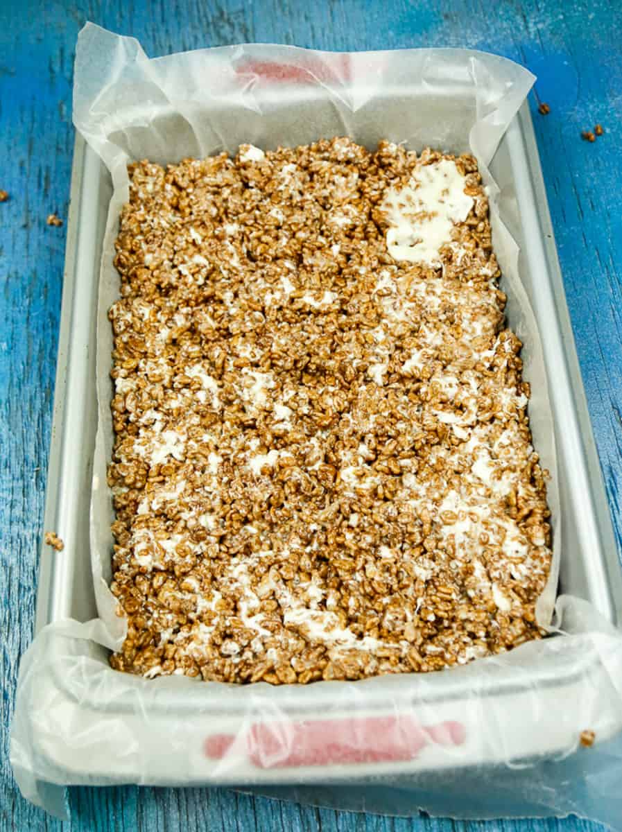 press rice krispie mixture evenly into a parchment lined baking pan 