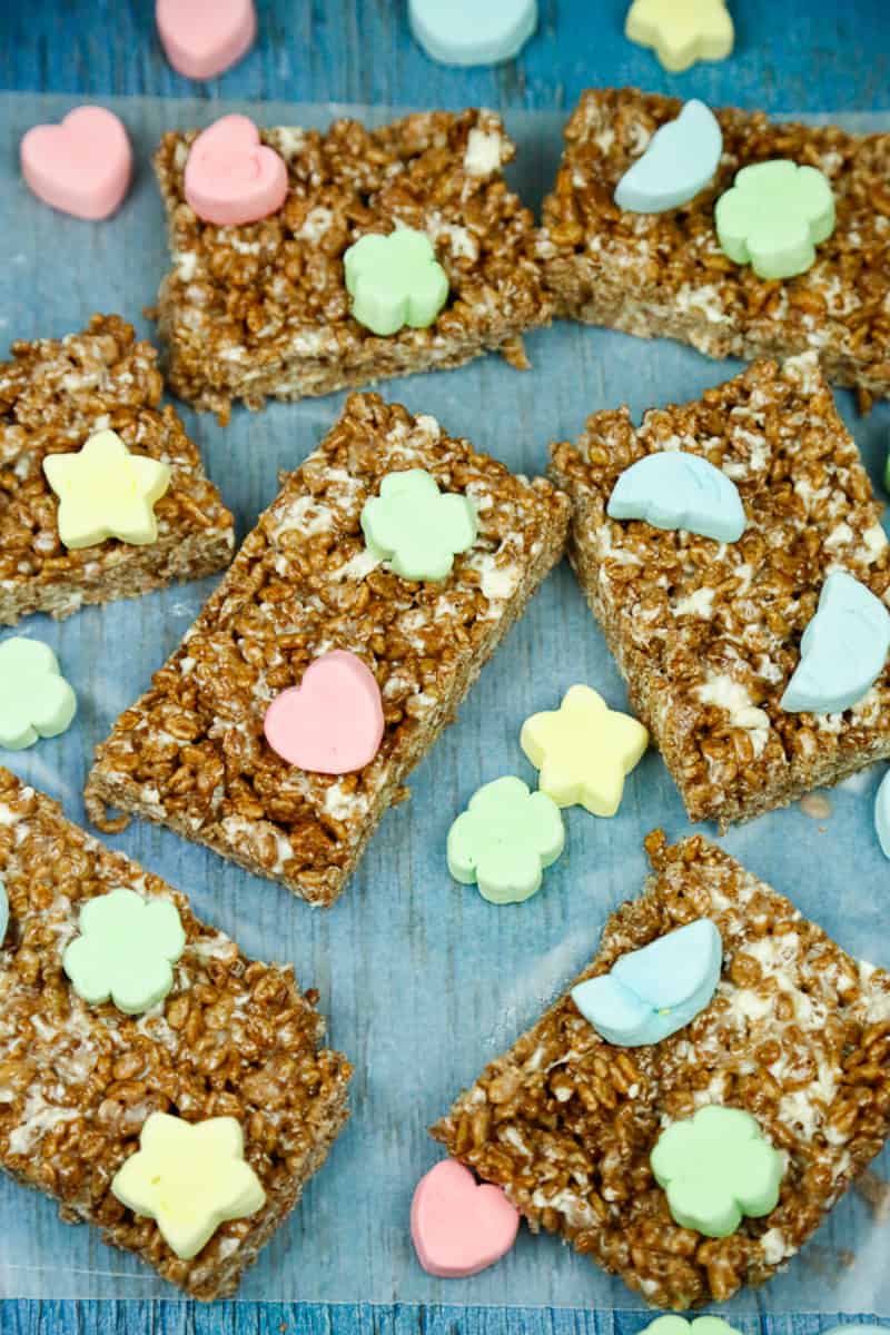 Chocolate rice krispies squares with colored marshmallows on them on a blue backdrop