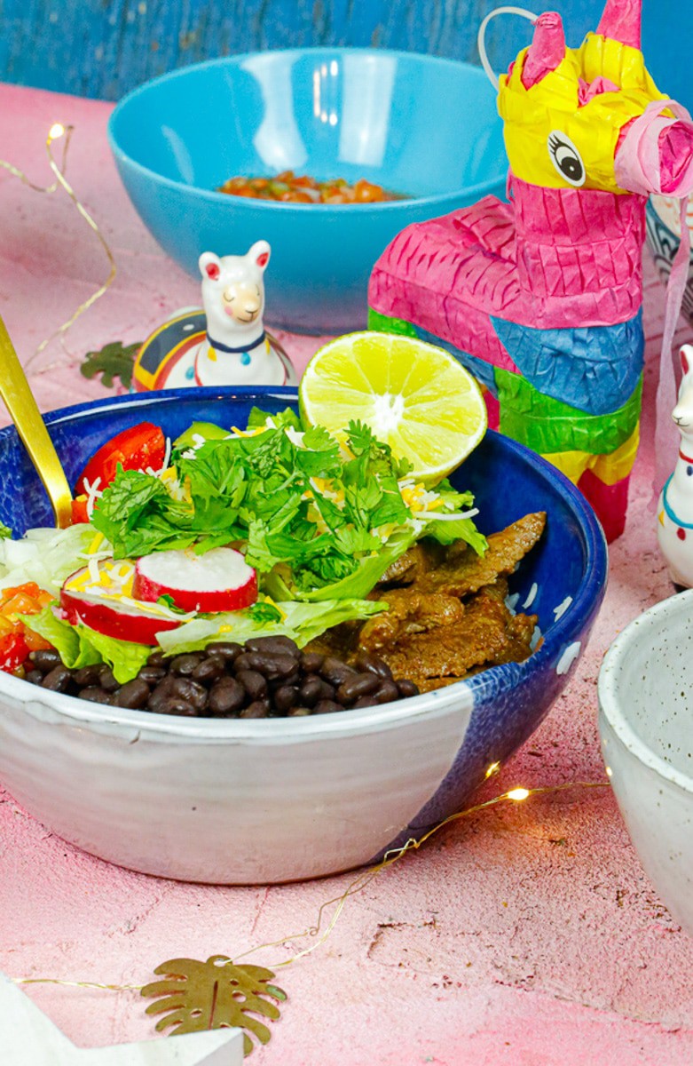 a closeup of ingredients for beef burrito bowls with salsa in the background on a pink back drop 
