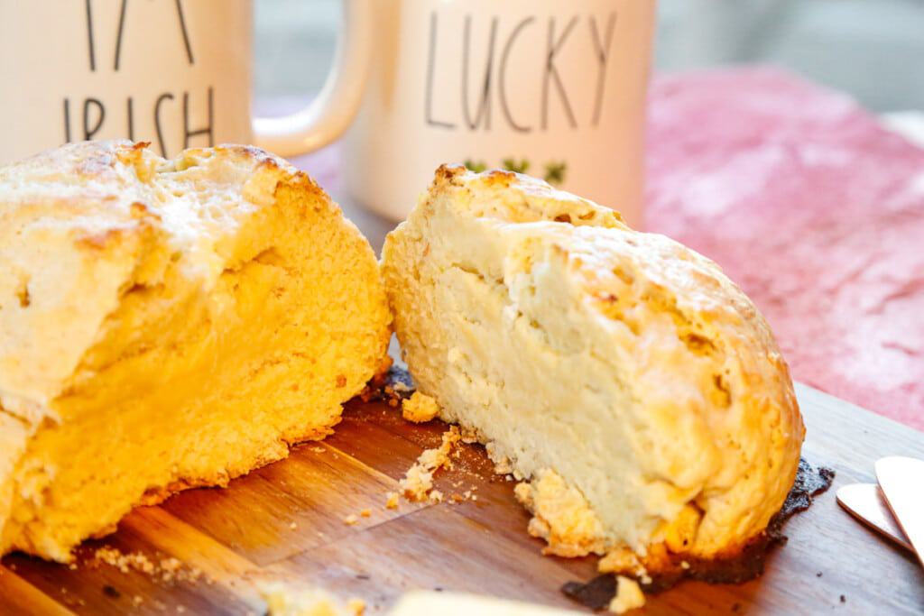 Open-faced soda bread with two mugs behind it 