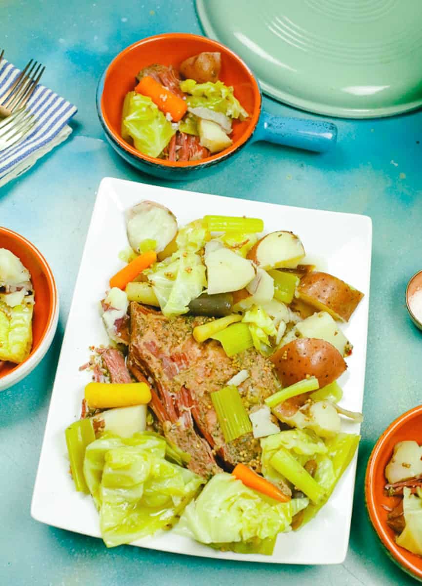 dutch oven corned beef and cabbage on a white plate with carrots and potatoes 