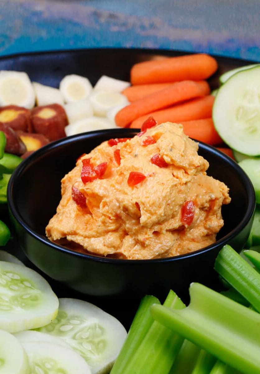 A tray of fresh veggies with homemade smoked pimento cheese with pimento on top 