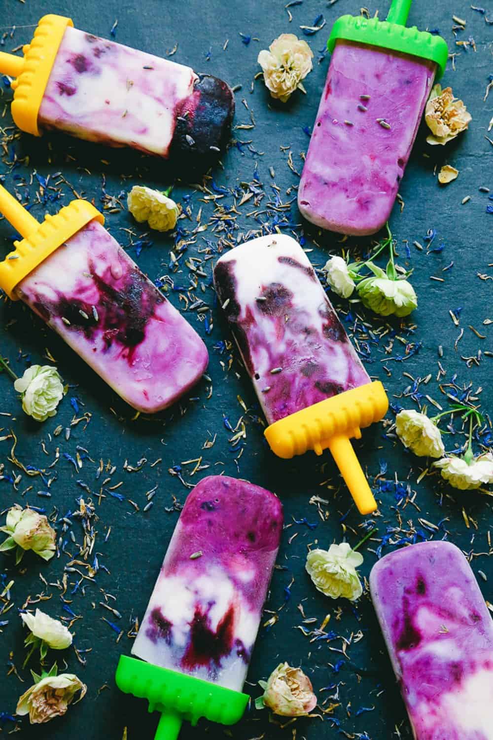 lavender blueberry coconut dairy free honey popsicles sitting on a black cutting board