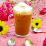 Shakerato Iced Coffee on a pink backdrop with sunflowers and a red flowers and coffee spoons