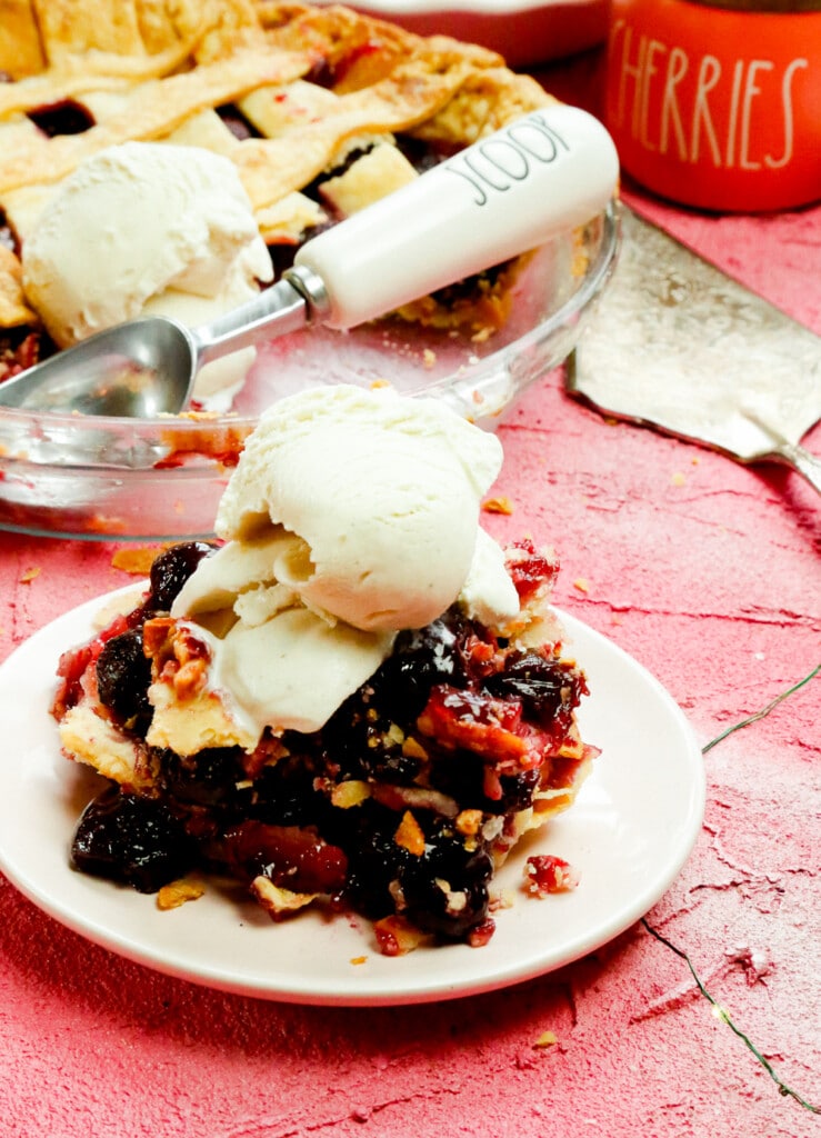 A slice of homemade cherry pie with a scoop of ice cream