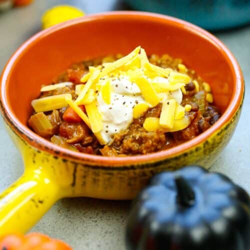 a bowl of pumpkin chili topped with sour cream and shredded cream