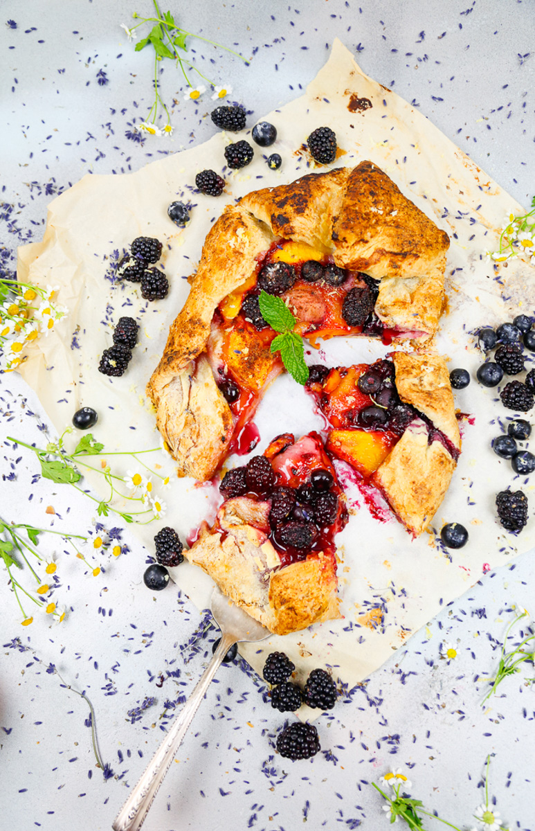 peach galette with puff pastry loaded with blackberries, blueberries, peaches and nectarines with a sprig of mint 
