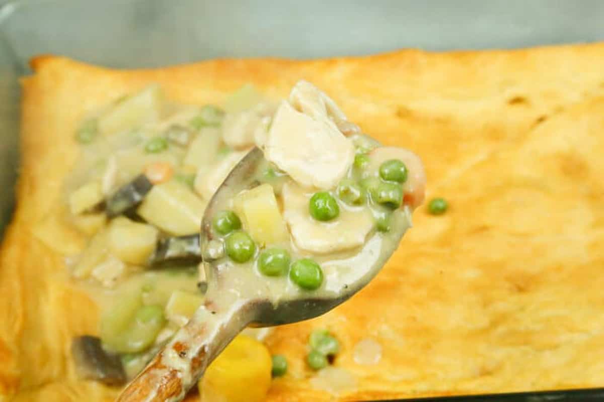 chicken pot pie filling on top of puff pastry in a baking dish 