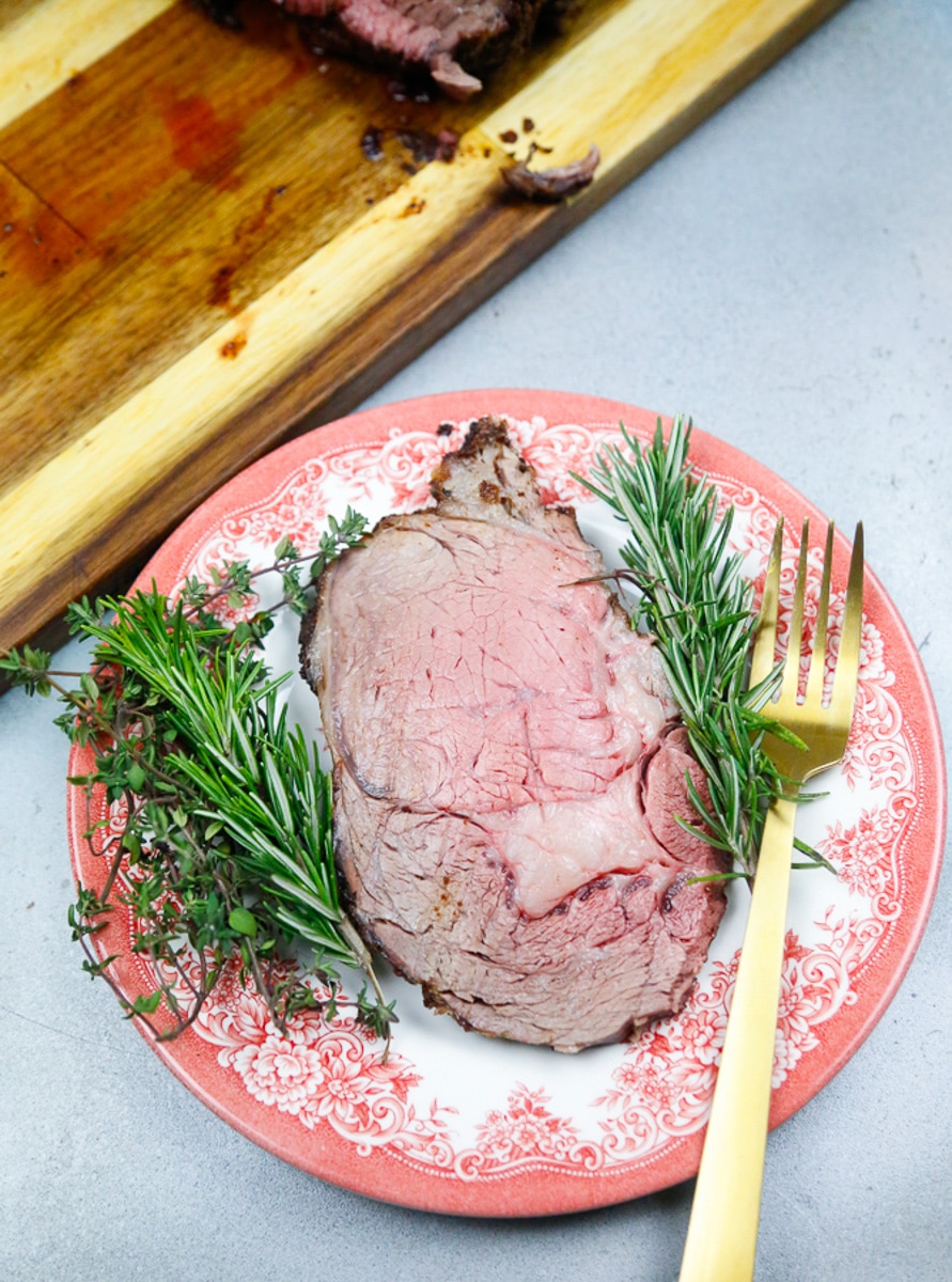a slab of perfectly cooked slab of prime rib with sprigs of fresh rosemary and 