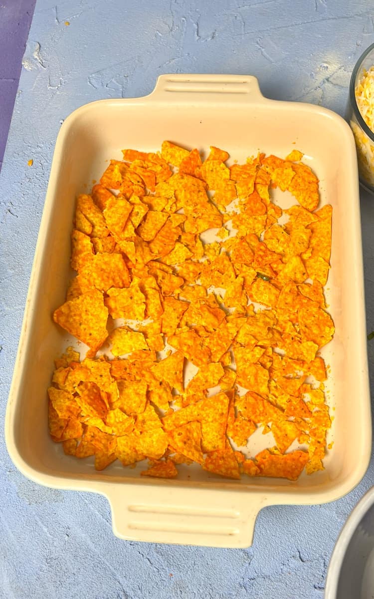 a layer of nacho cheese Doritos in the bottom of a casserole dish 