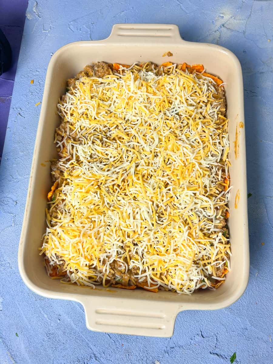 A layer of Mexican shredded cheese to the beef layer in a casserole dish 