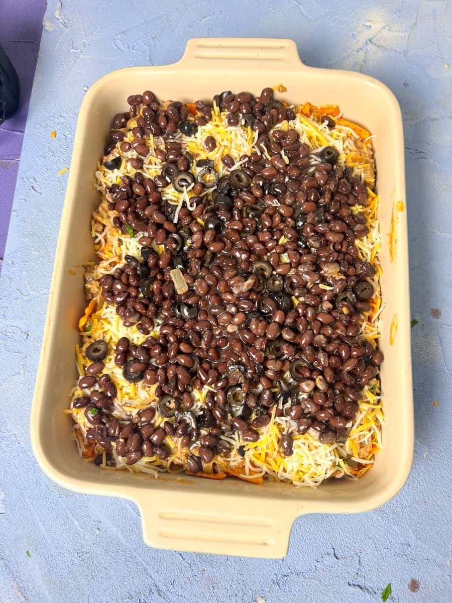 black beans on cheese and beef layers in a casserole dish 
