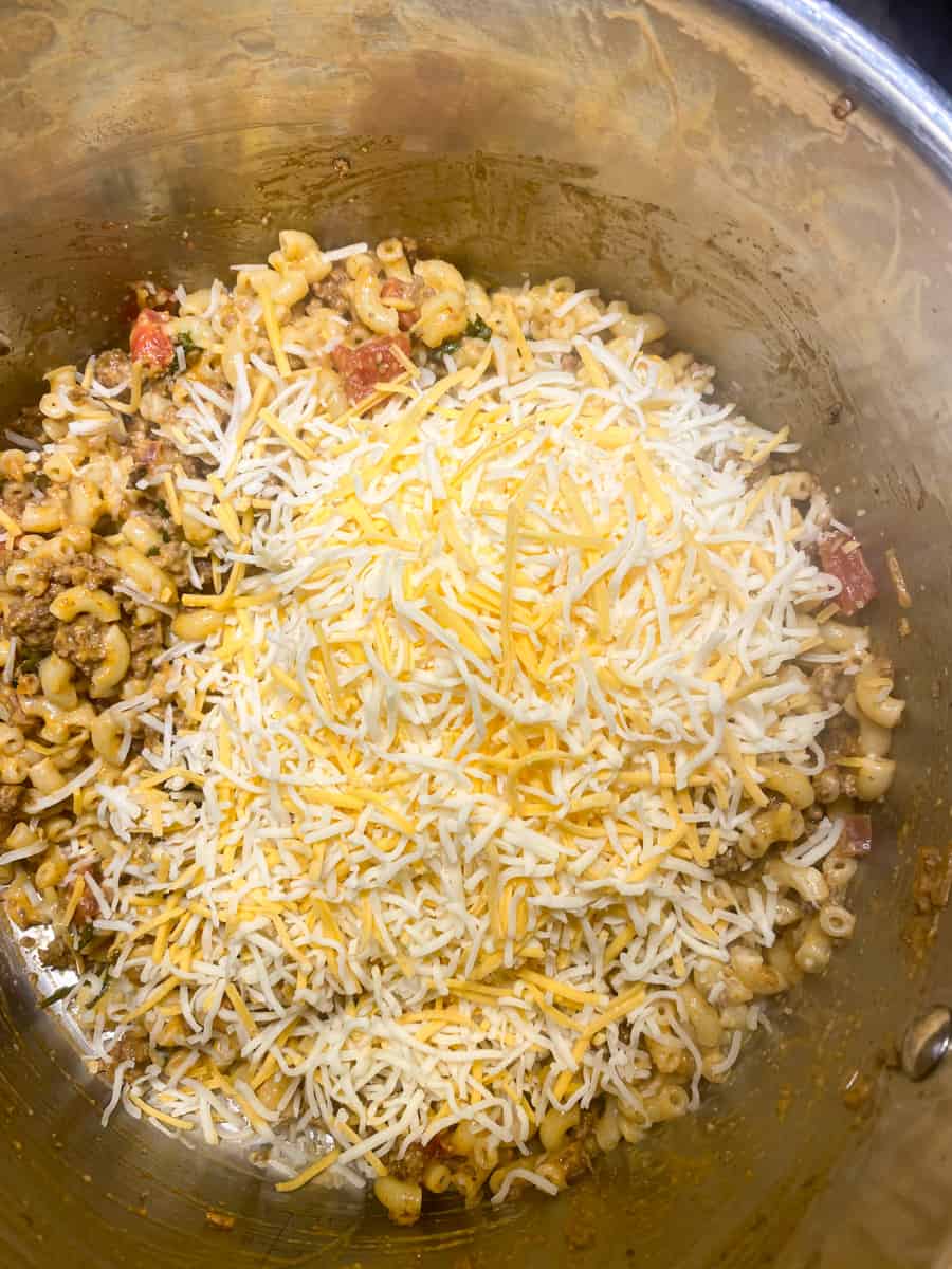 Mexican shredded cheese, macaroni noodles being combined with taco ground beef 