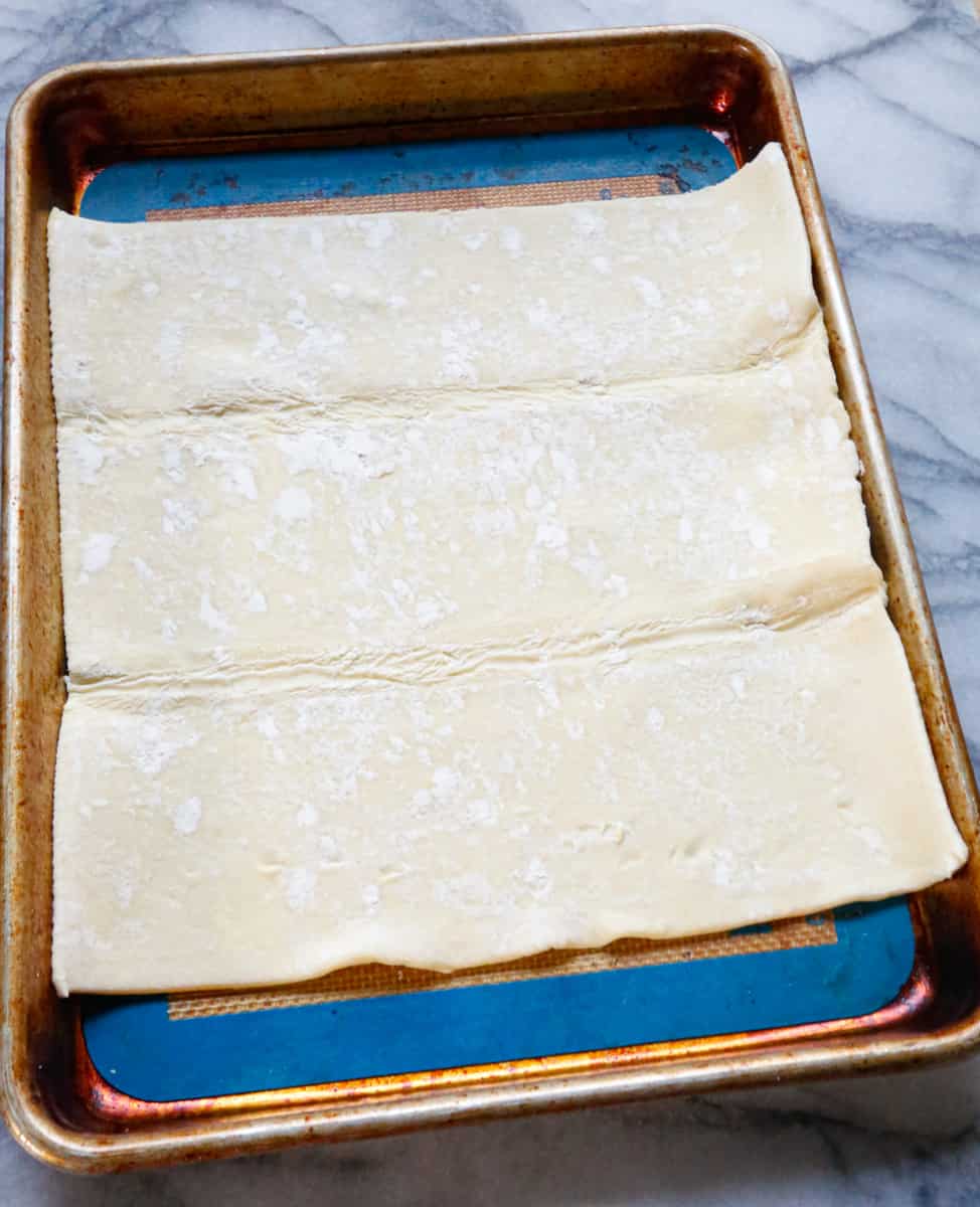 Thawed puff pastry on a parchment lined baking sheet