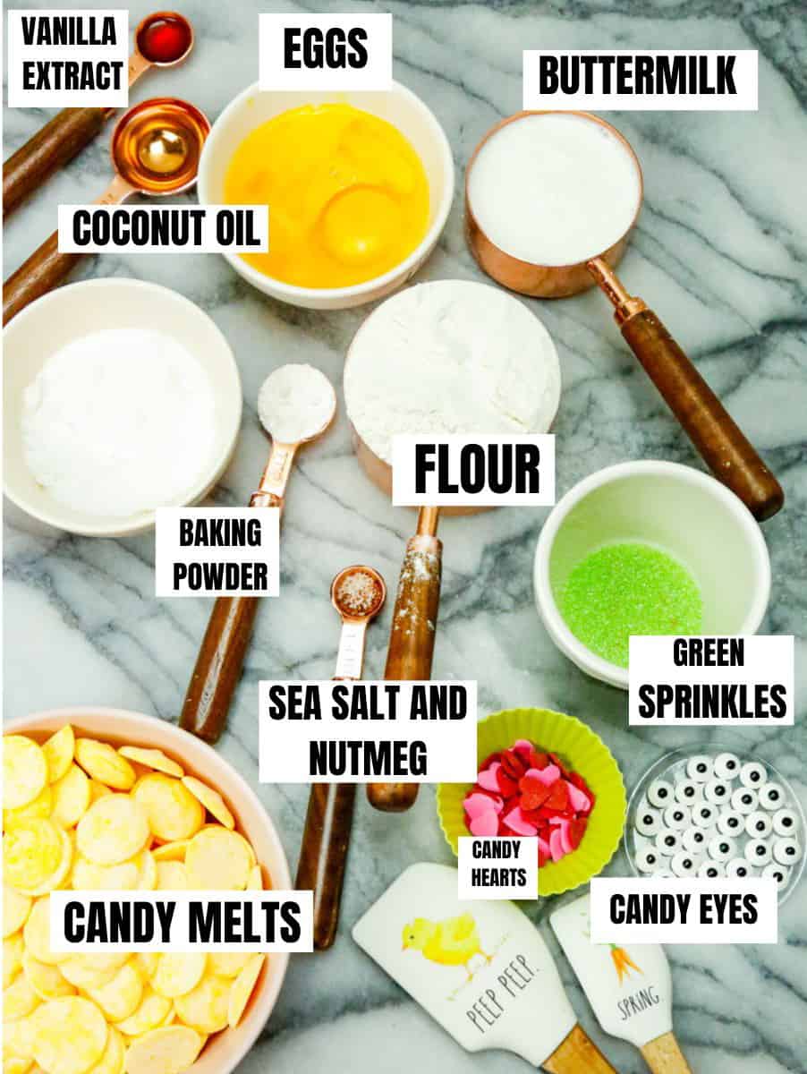 Ingredients for healthy baked donuts recipe buttermilk, green sprinkles, flour, baking powder, coconut oil, eggs, vanilla extract, sour cream, candy melts, candy eyes, candy hearts, sea salt and nutmeg 