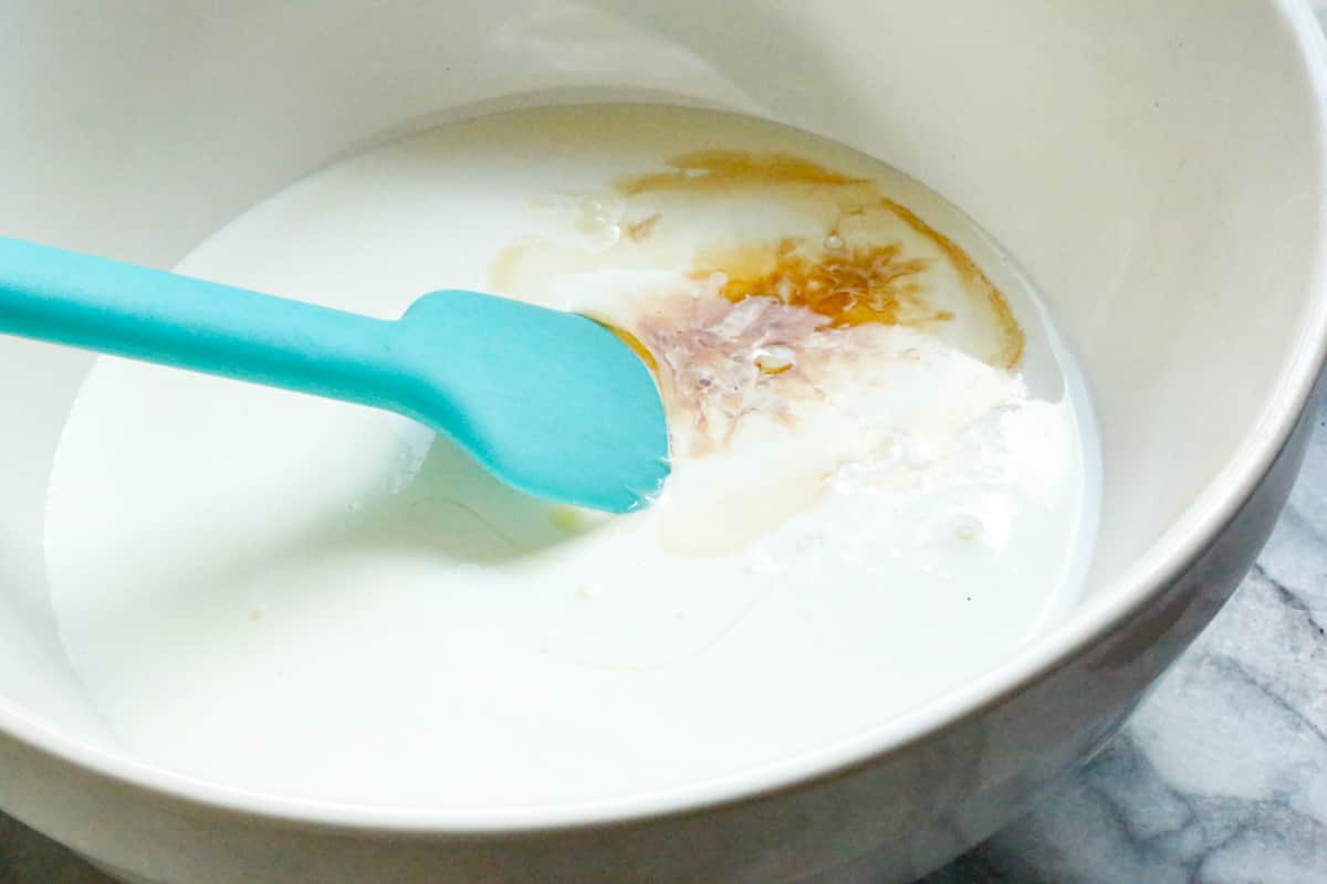 heavy cream, condensed milk, and vanilla extract in a mixing bowl with a spatula 