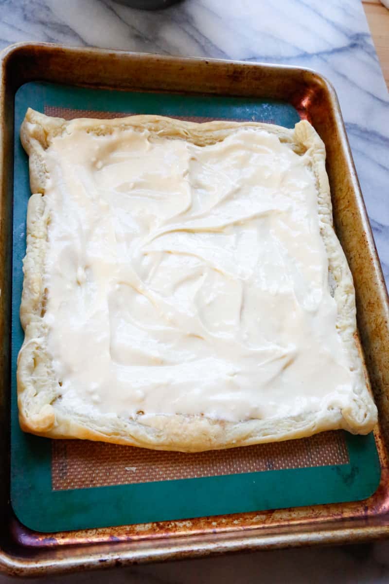 cooked puff pastry boat on a baking sheet filled with cream cheese filling for strawberry turnovers 