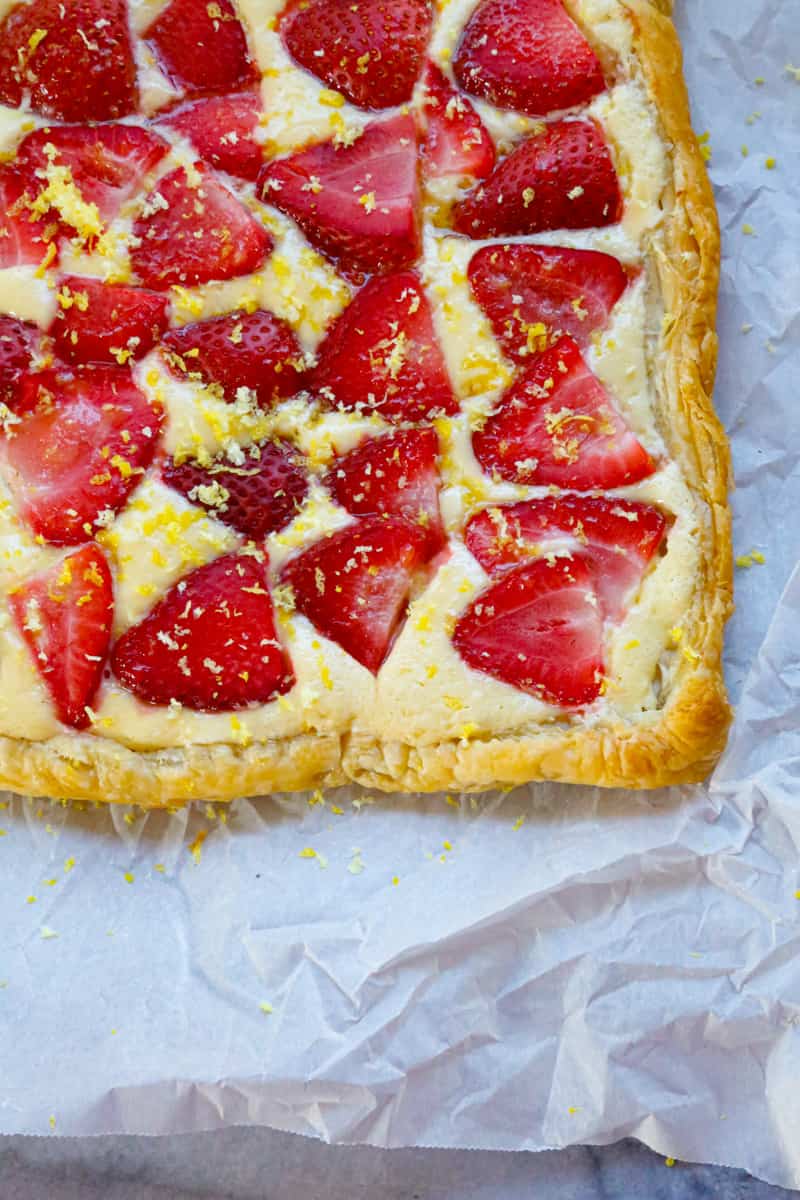baked strawberry turnover on parchment paper on a marble back drop 