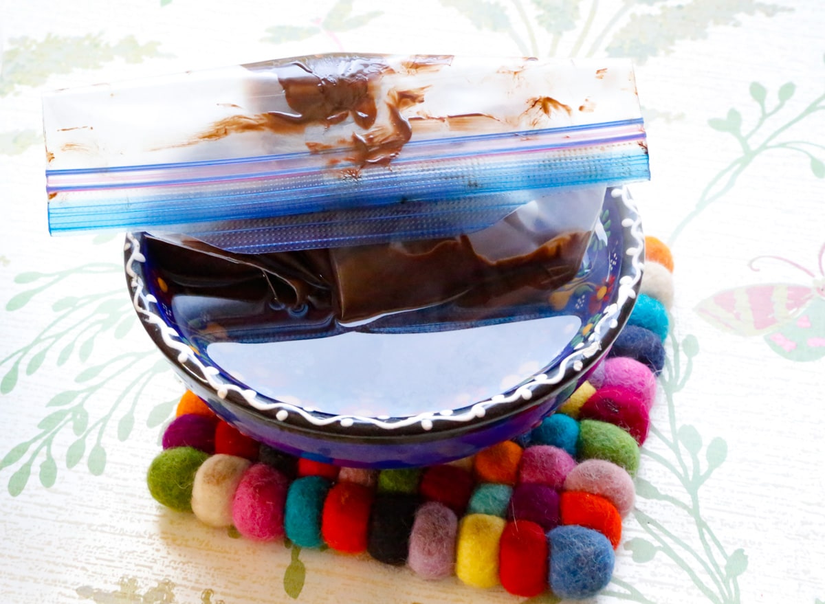 store the melted chocolate in a ziplock bag in a bowl of warm water 