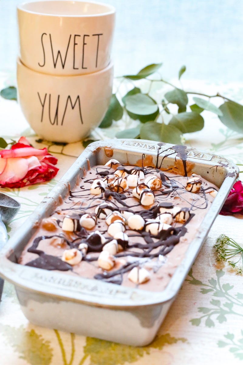 a tray of homemade chocolate marshmallow ice cream with a metal ice cream scoop and the words sweet and yum and dried flowers 