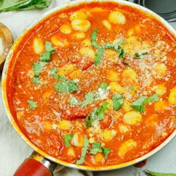 gnocchi marinara in a skillet with fresh basil leaves and parmesan