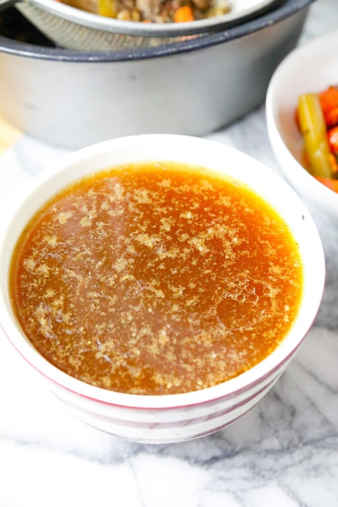 a bowl of homemade bone broth on a marble counter top