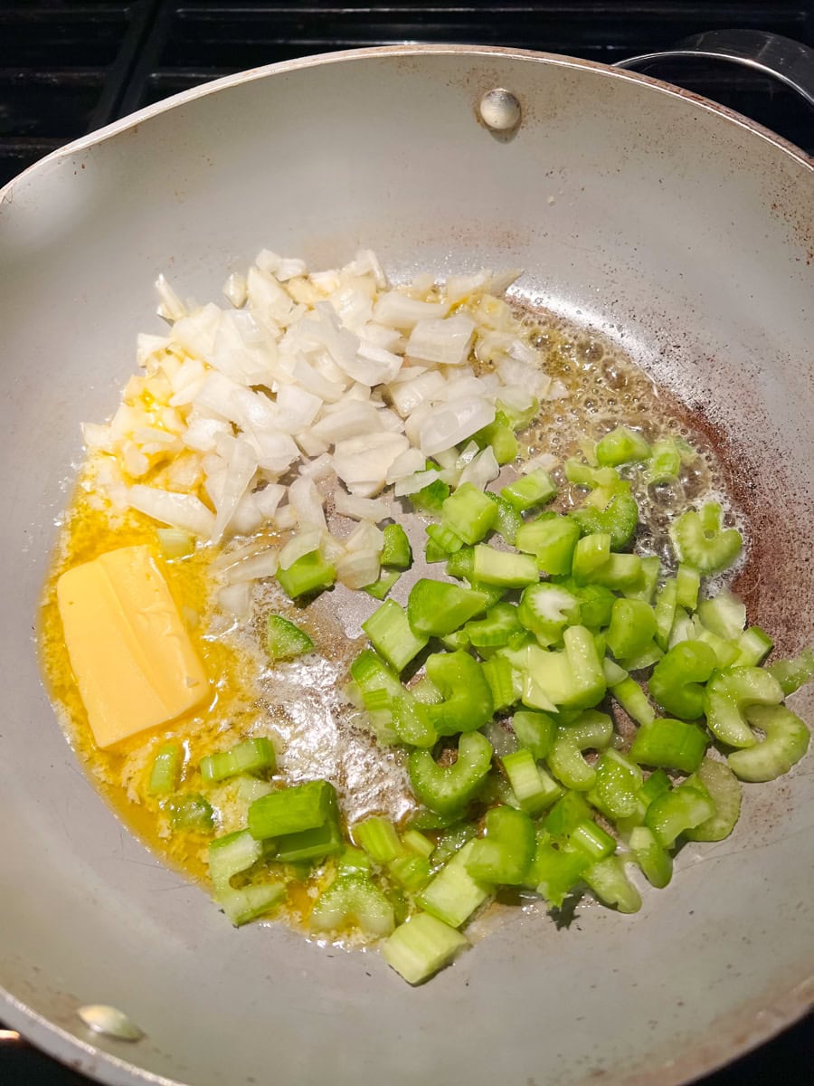 a frying pan with butter, chopped cerlery and chopped onion