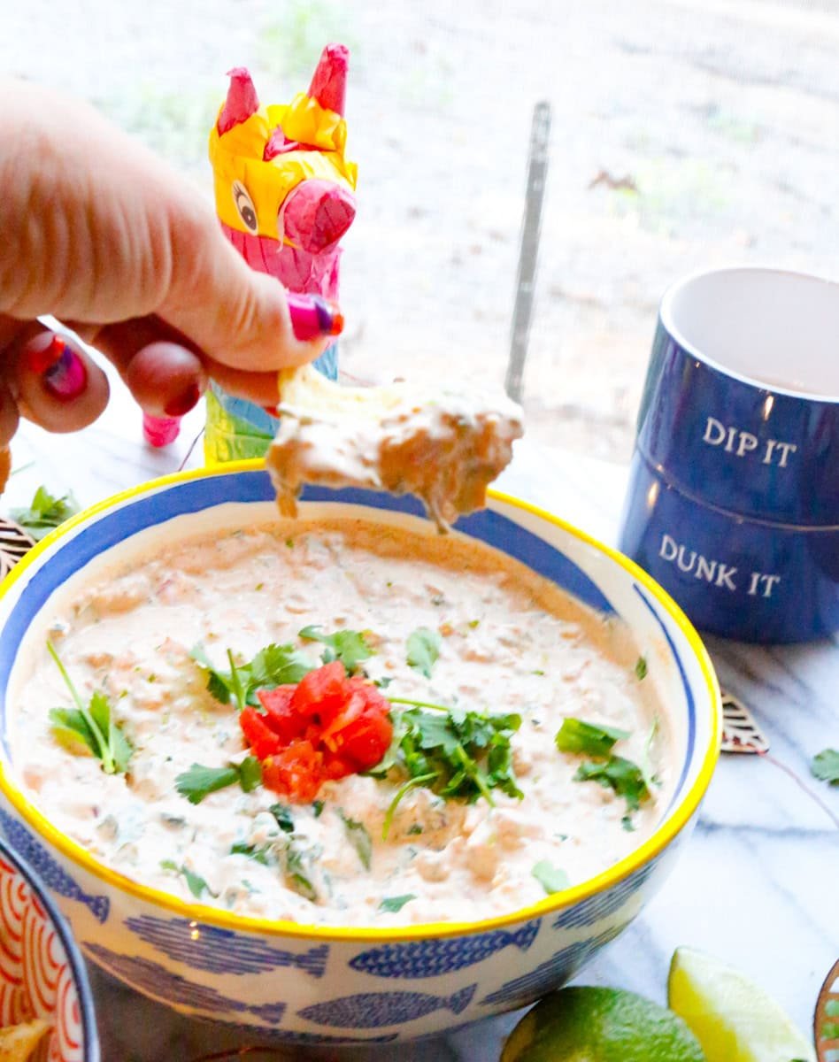 A bowl of TikTok Boat Dip Recipe with a tortilla chip being dipped into it 