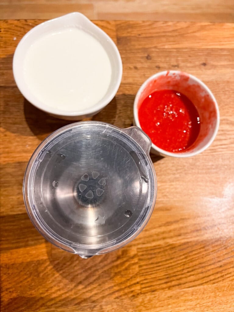 In the cold foam machine, add the homemade raspberry syrup, maple syrup, and heavy cream and milk and froth until well combined. The raspberry cold foam will be nice and thick.