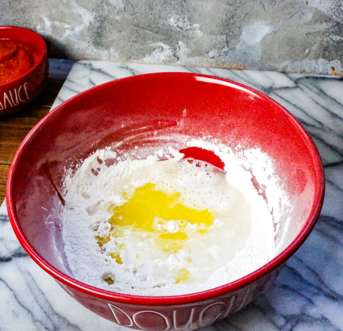 Add the wet ingredients to the dry ingredients and pour in water and olive oil and stir well until it forms a sticky dough, but you don't want the dough to be watery.