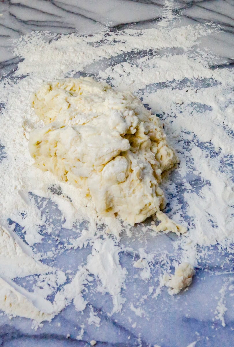 Remove the dough from the mixing bowl and place on a floured surface and knead the dough lightly. Don't over knead the dough! You want the dough to be smooth, not sticky. Knead the dough on a floured surface for one to two minutes until dough is no longer sticky or watery.