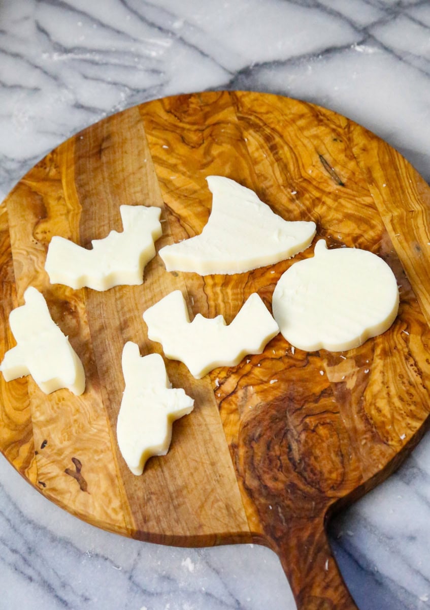 a wooden backdrop of Mozzarella ghosts, mozzarella halloween cheese slices