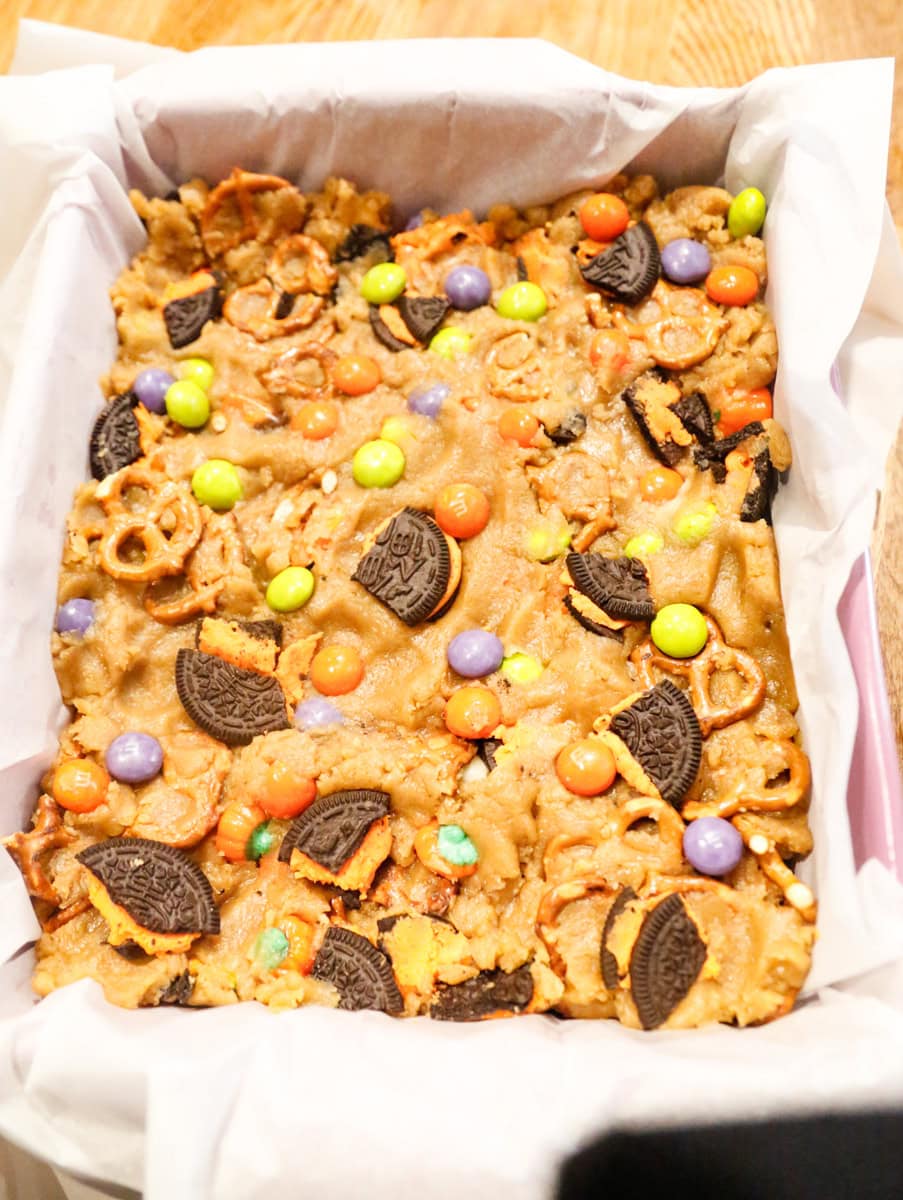 Spread batter evenly in prepared baking pan. Sprinkle with remaining ¼ cup pretzels, 1 cup cookies, and 2 tablespoons chocolate chips.