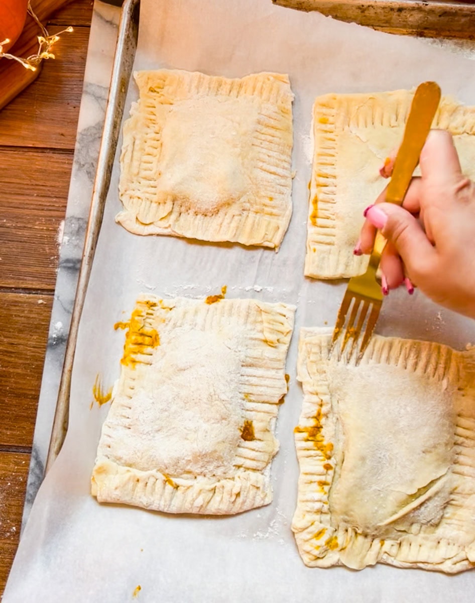 Carefully place the top rectangle on top of the pumpkin filled side and use a fork crimp the sides of the puff pastry together.