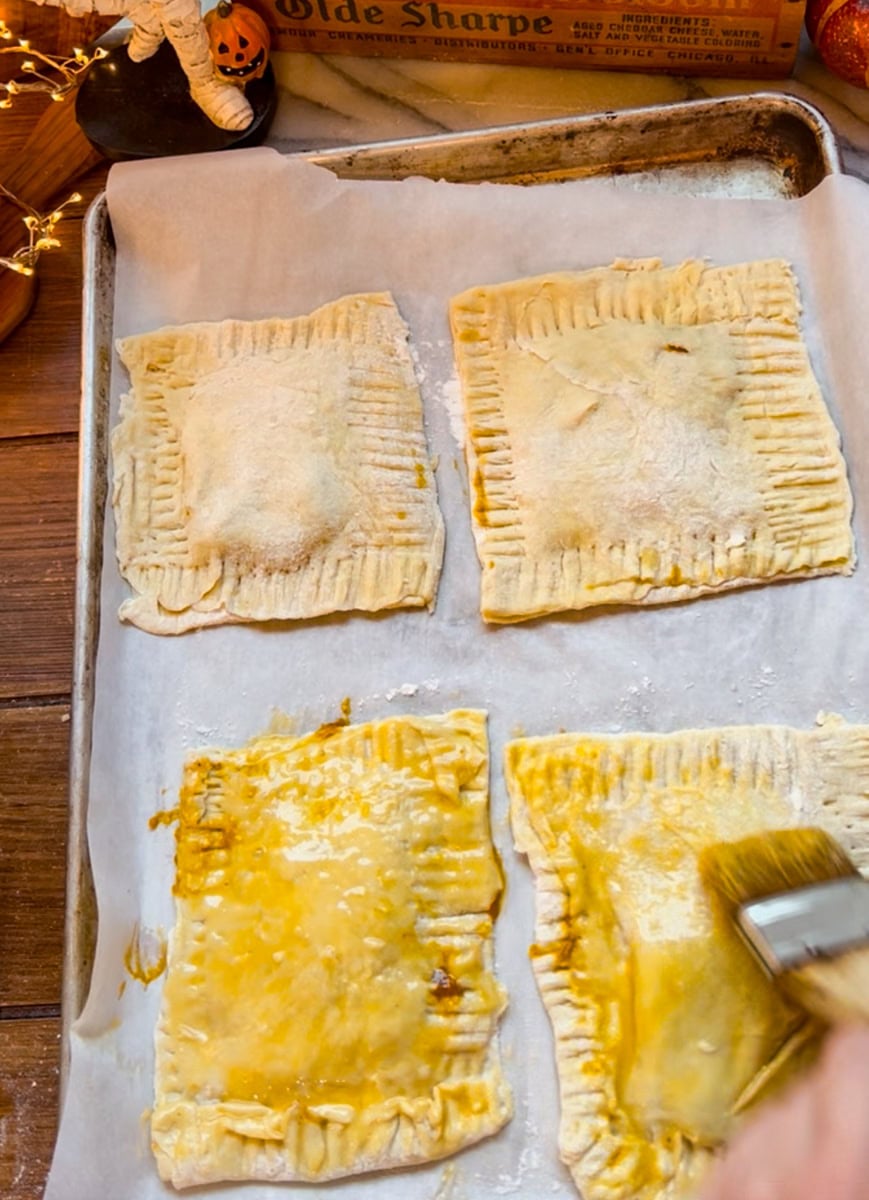 Brush the prepared pop tarts with egg wash. This will ensure the pumpkin pie pop tarts turn out shiny, with a flaky crust and golden brown.