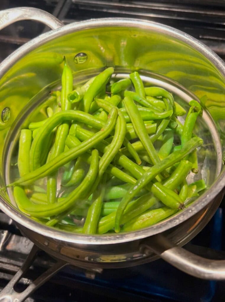 First: steam the green beans in a double broiler filled with water. Don't over steam them! Over-cooking the green beans will keep them from being crispy and we want them crispy. Steam them for 3-minutes then transfer to a sprayed casserole dish.