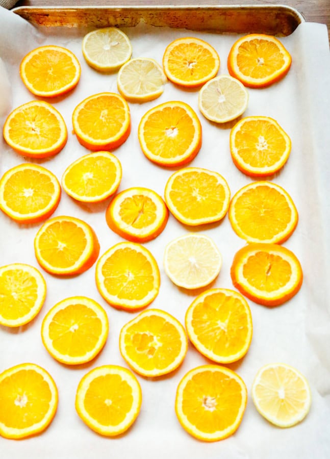 Slice and dry the orange and lemon slices. You'll want to slice them into ½-inch slices using a sharp knife and lay them on a parchment lined baking sheet and pat them dry with a paper towel to remove excess juices.
