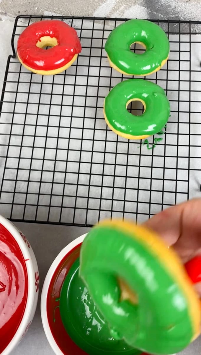 Dip each donut in the red or green glaze and place on a wire rack so that the frosting can drip off. Do this step quickly as we need to add the sprinkles immediately before the frosting sets on the donuts.