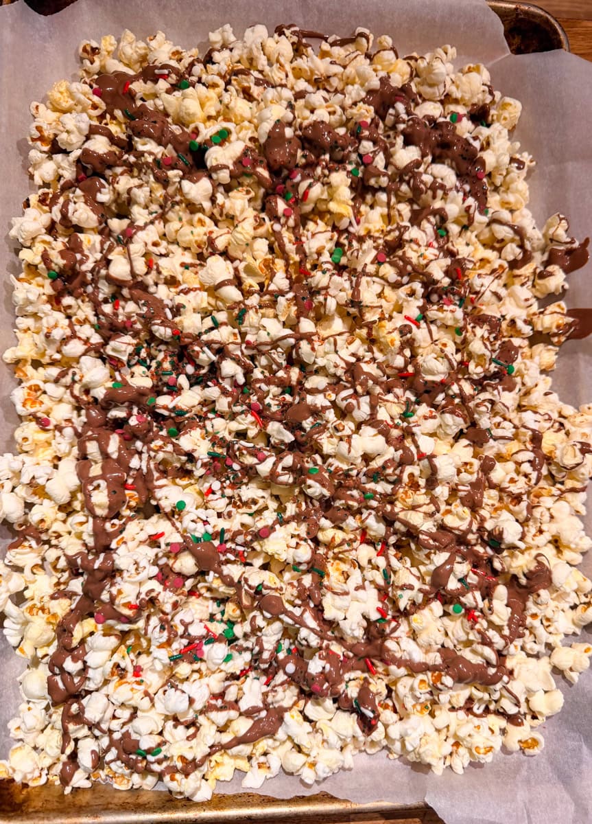 Spread the popcorn on the prepared parchment lined baking sheet. Drizzle the melted chocolates on the popcorn.