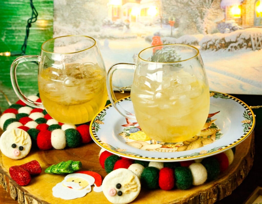 two glasses of ginger ale in a glass Santa mugs on Christmas coffee holders