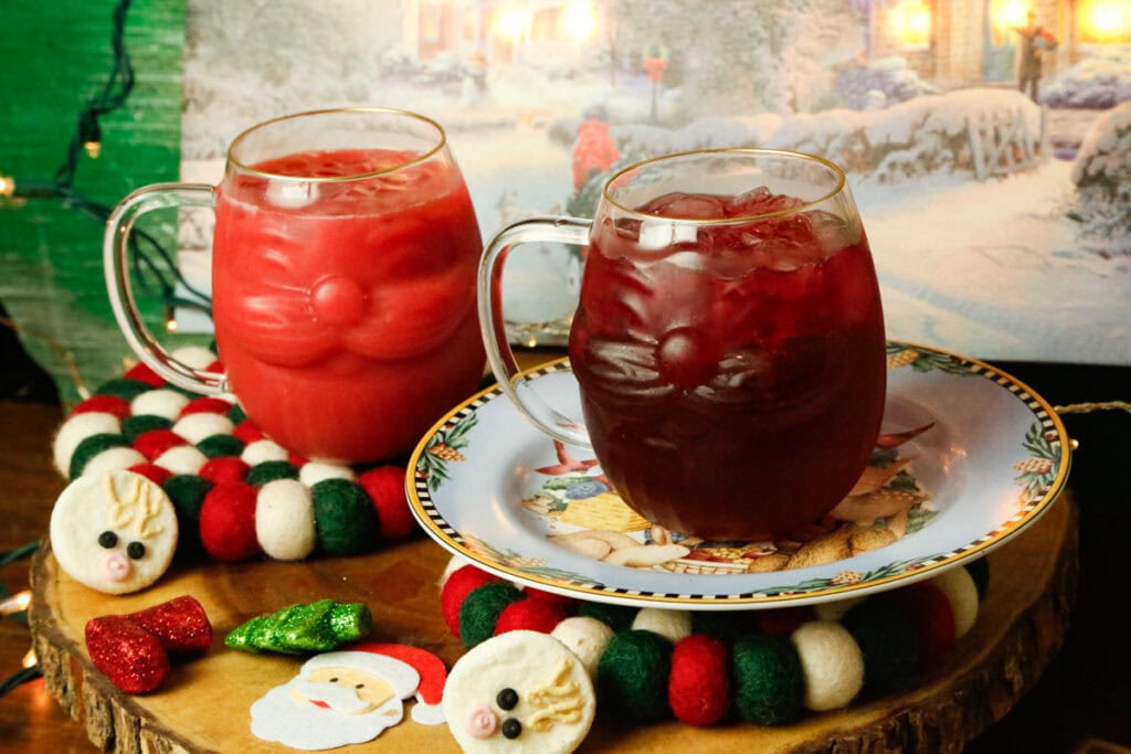 Add 2 tablespoon grenadine to each and gently swirl.
4️⃣ Pour ¼ cup cranberry juice into each glass.
Drizzle 2 tablespoon vanilla sweet cream on top to create a Santa hat “fluffy edge.”