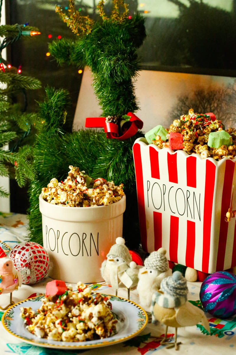 Two buckets of Easy Christmas popcorn in Rae Dunn popcorn tins