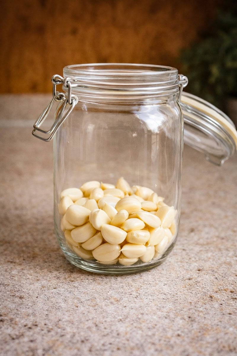 Glass jar filled with fresh peeled garlic cloves for making fermented garlic honey 