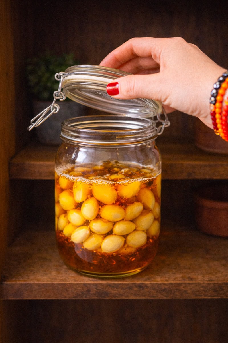 Opening the lid of a glass jar of garlic and honey to release gases during the fermentation process