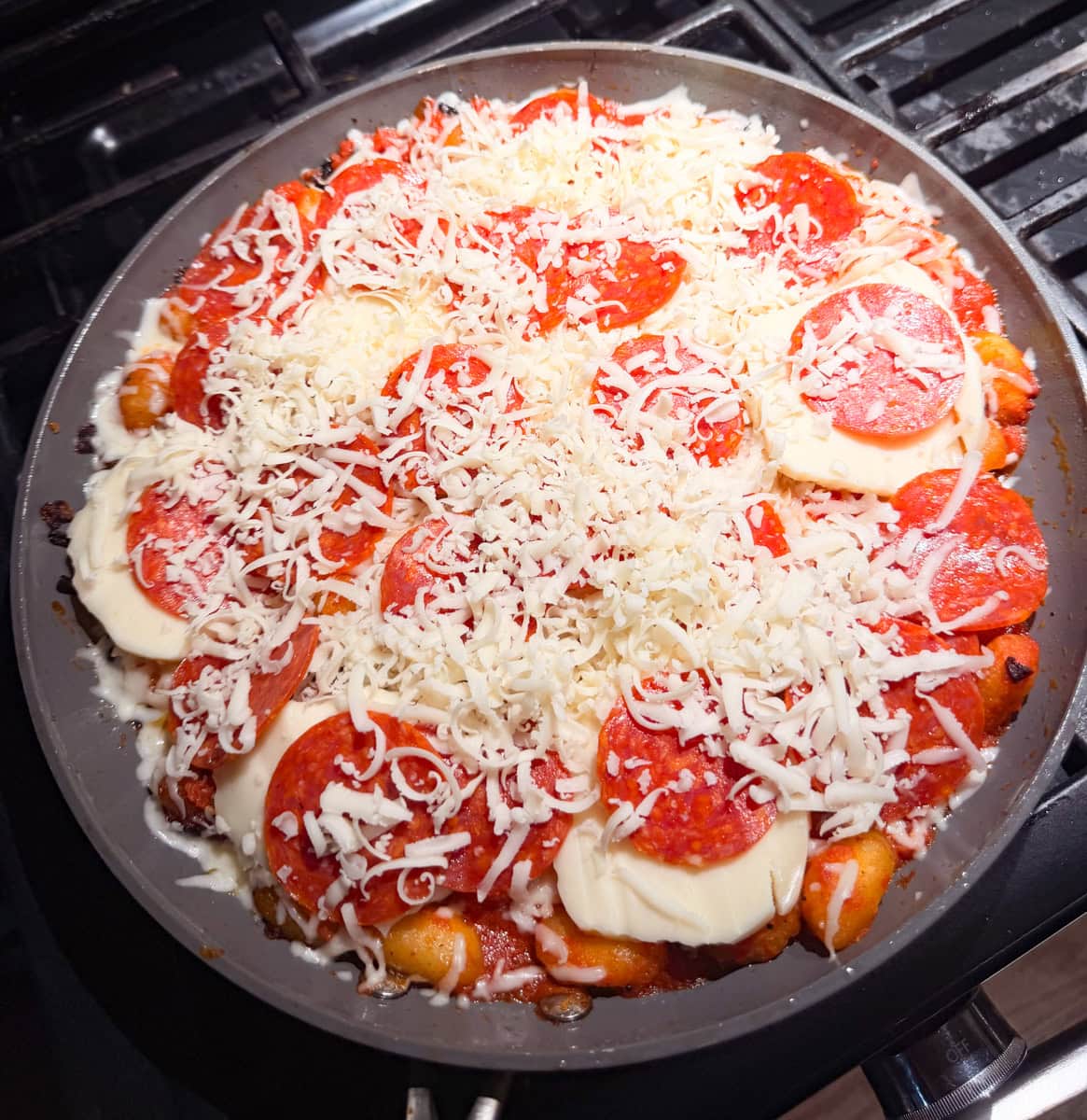 Take the Mozzarella slices and place them on top of the gnocchi and layer in the remaining pepperoni slices. Top with remaining shredded Mozzarella cheese.
