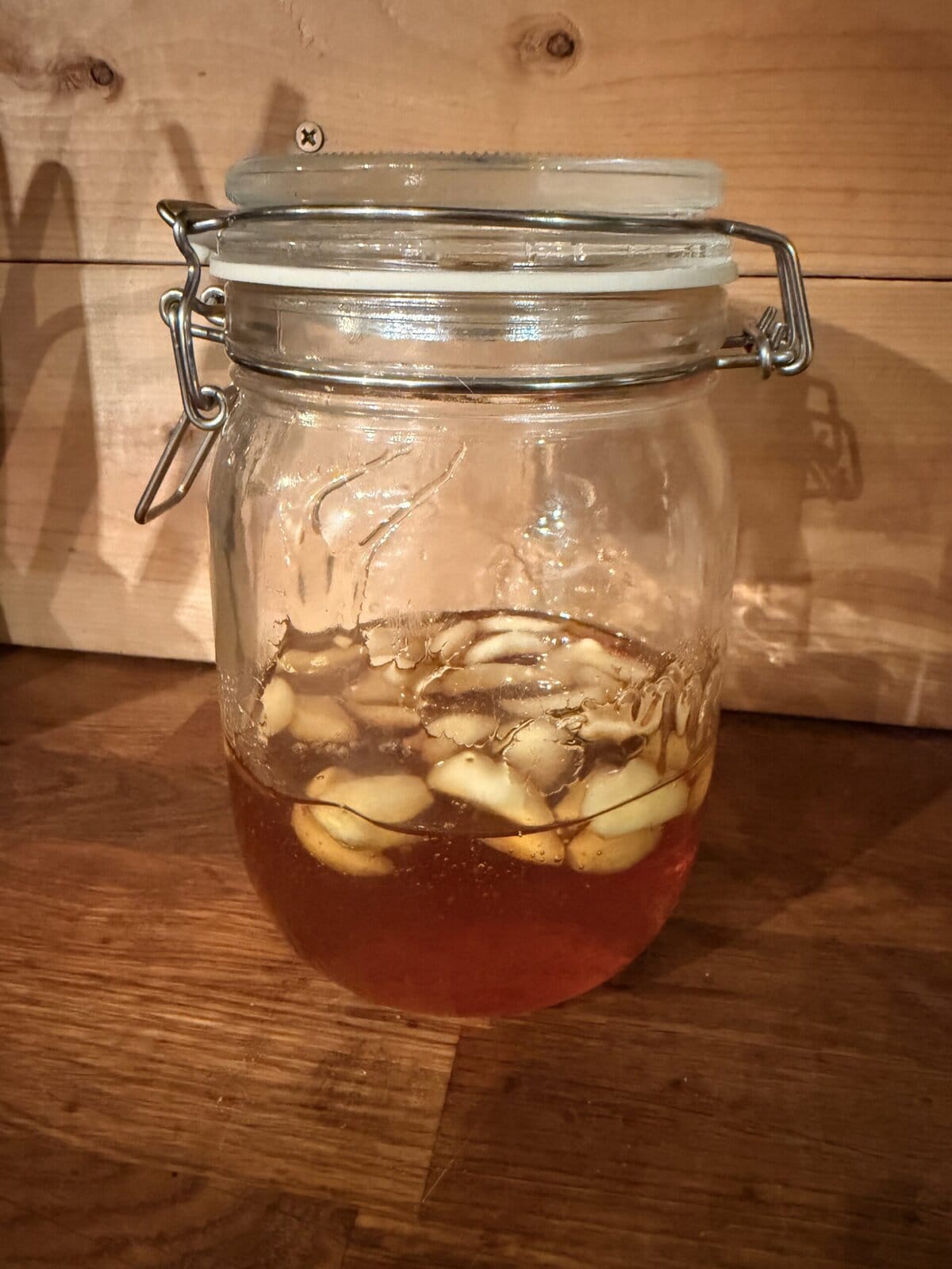 Glass jar of garlic and raw honey stored in a cool dark place at room temperature during fermentation