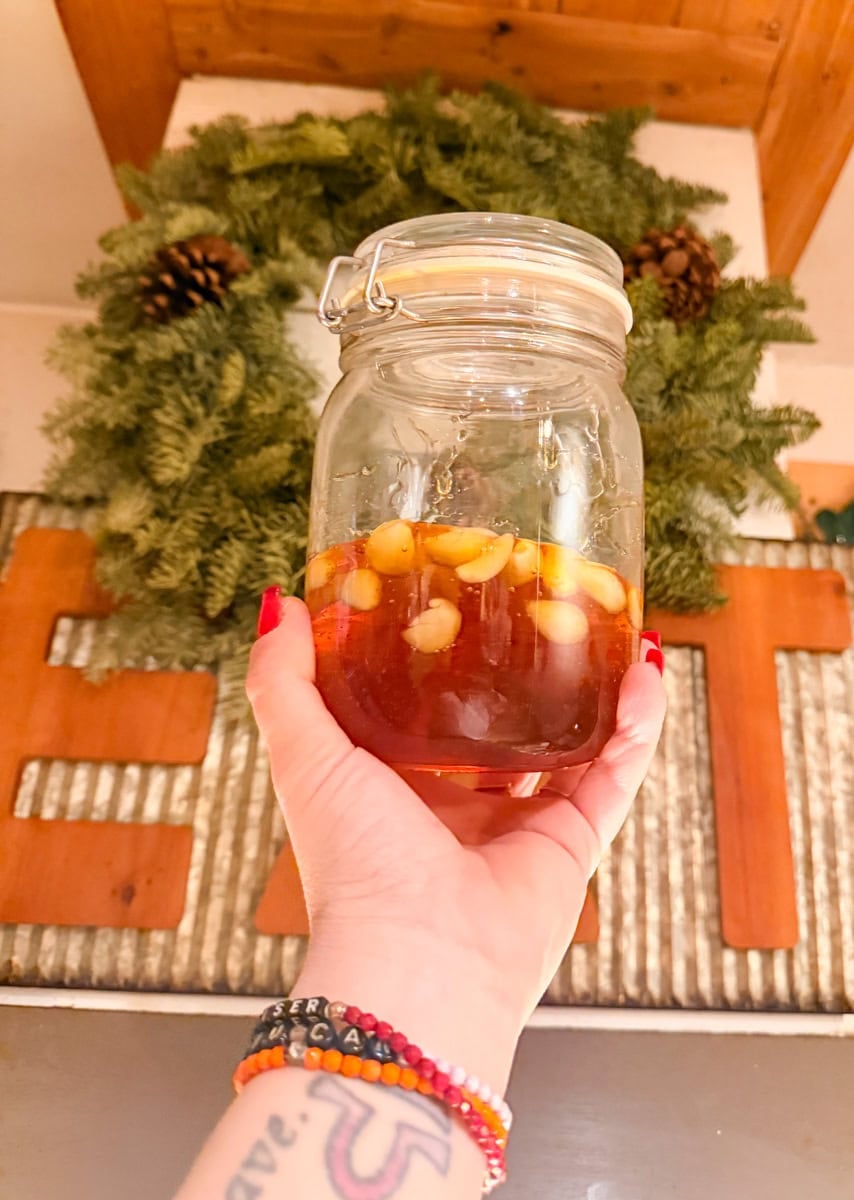 Jar of fermented garlic honey with garlic cloves submerged in raw honey during the fermentation process 