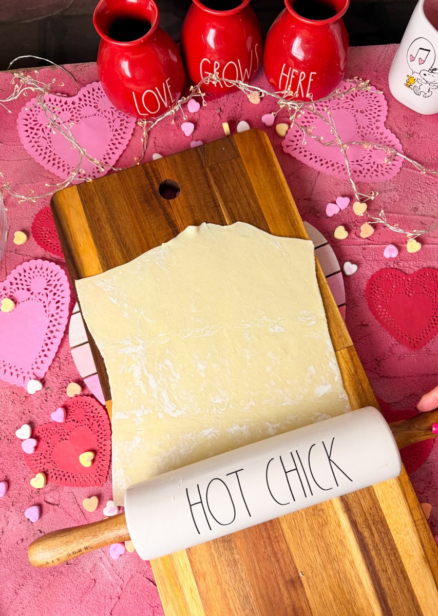 Store-bought puff pastry sheet rolled out on a cutting board, ready to cut into heart shapes for strawberry cream cheese danish recipe